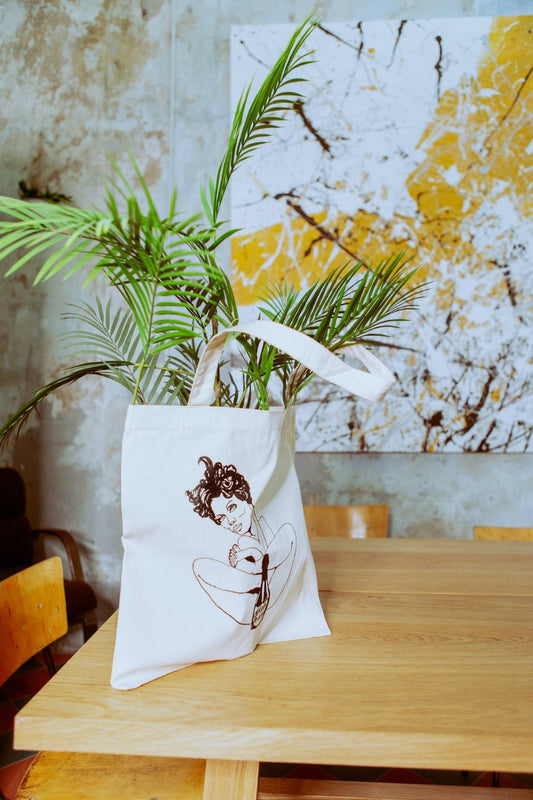 “Male Tears” Natural Tote Bag placed on a table, highlighting its natural color and spacious design